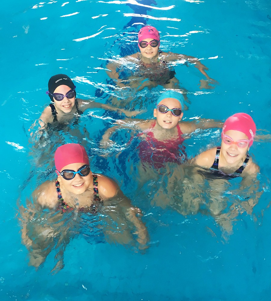 gyerekek egy medencében úszósapkában